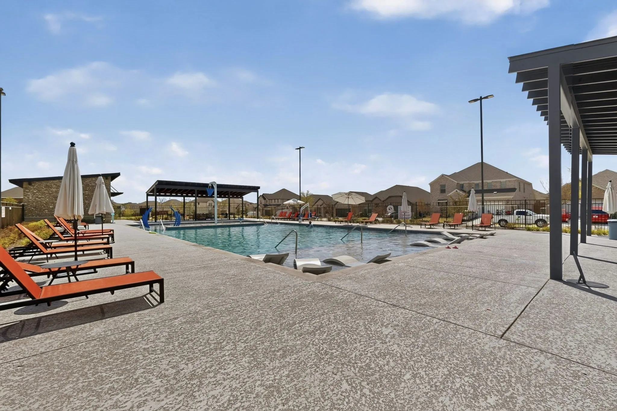 Expansive community pool with integrated lounge areas and a textured concrete deck