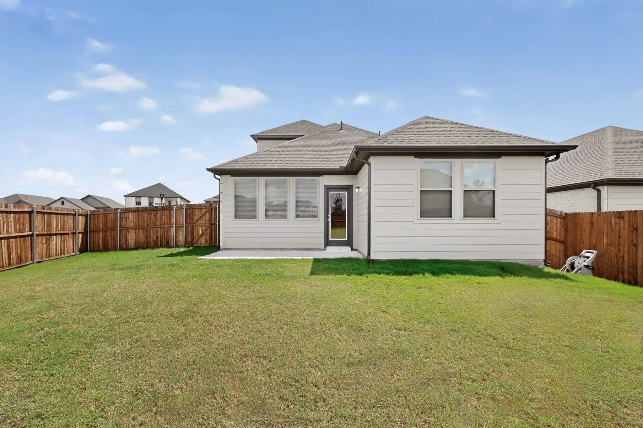 Expansive backyard with wood fencing, a concrete patio, and a light-colored siding exterior