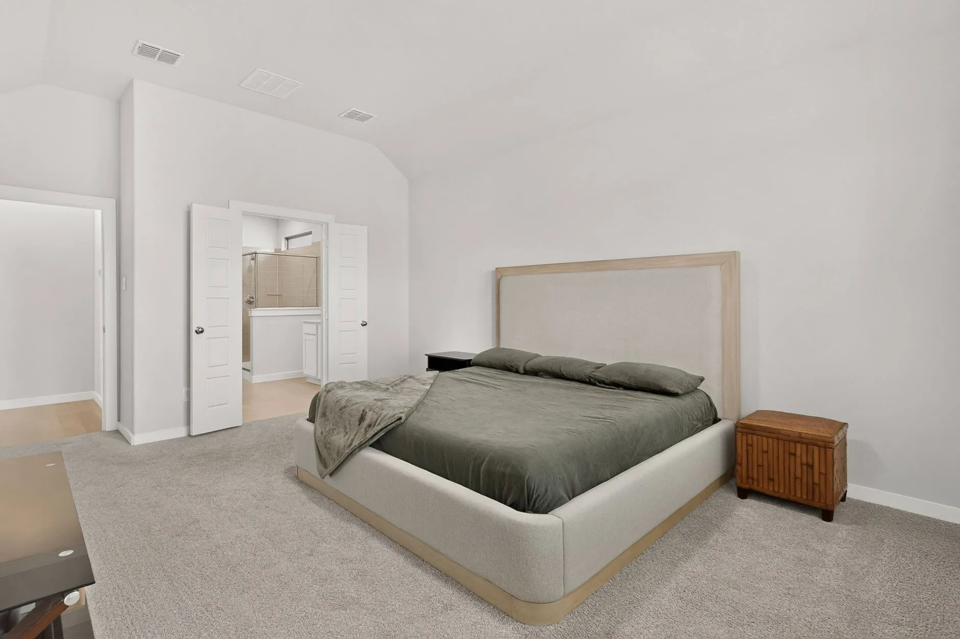 Spacious room featuring vaulted ceilings, light-toned carpeting, and white painted walls