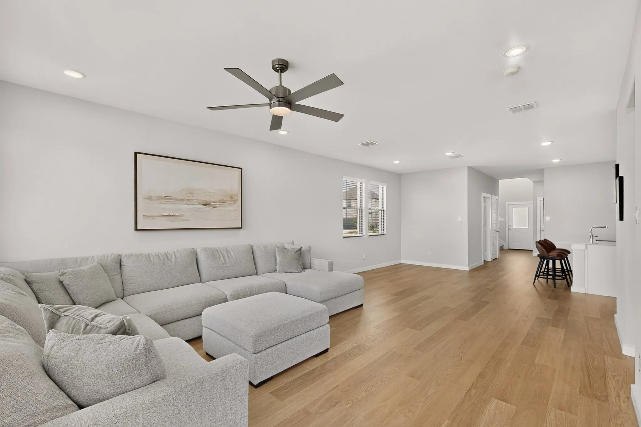 Open-concept living space featuring wood-finish flooring, recessed lighting, and a ceiling fan