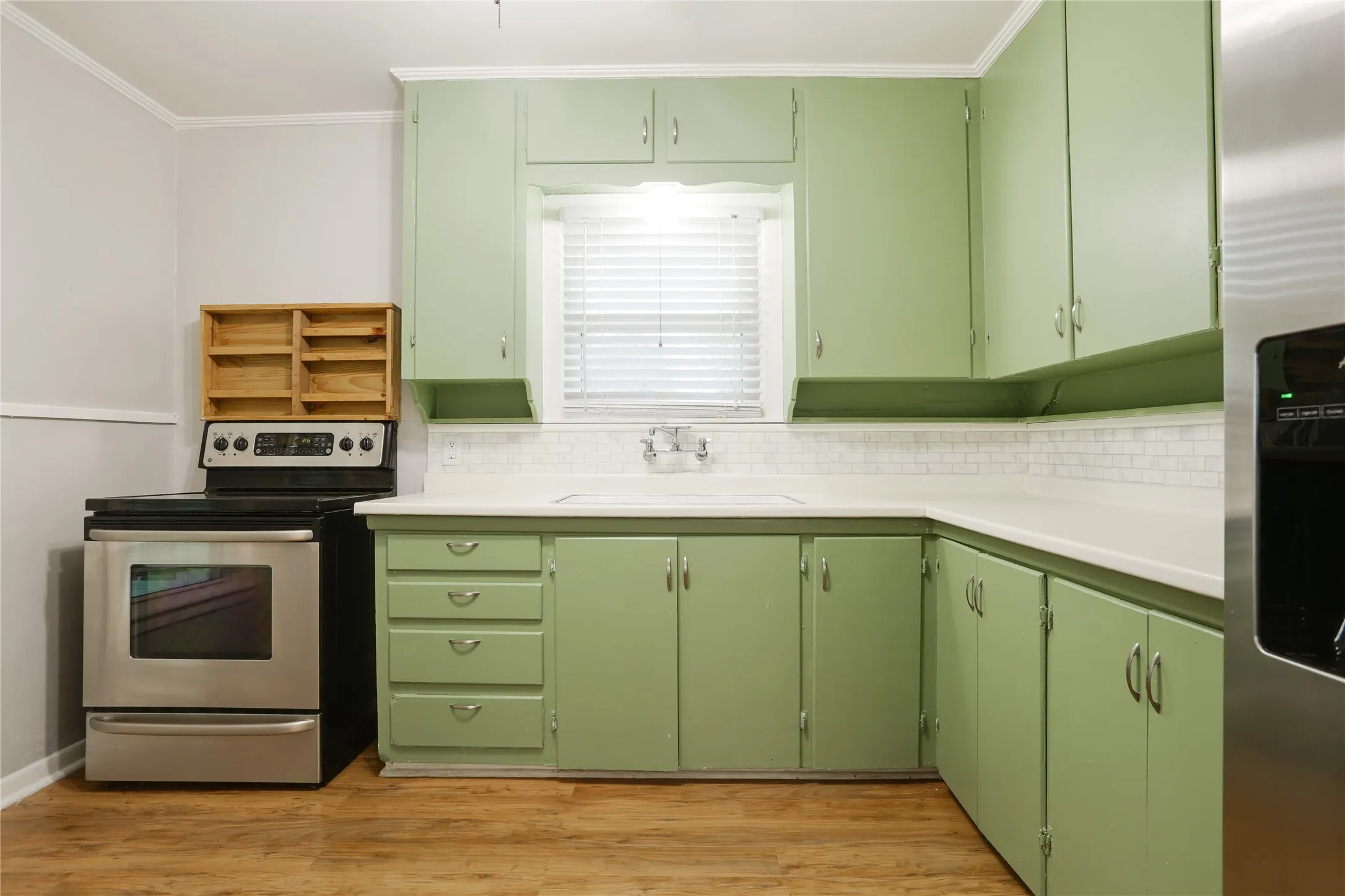 Kitchen featuring green cabinetry, wood-finish flooring, white countertops, and a white subway tile backsplash