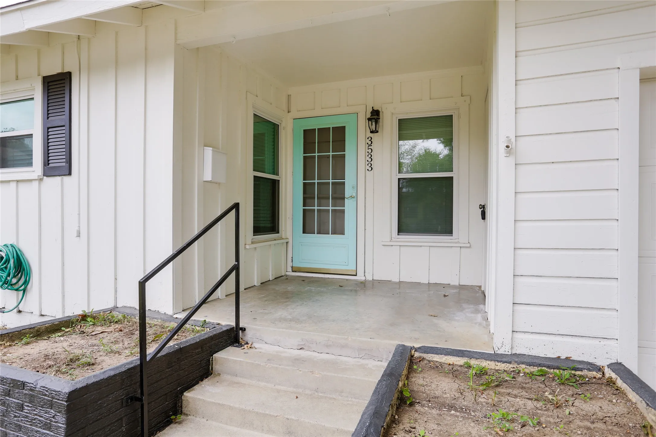 Covered entryway with concrete steps, wrought iron railing, and a vibrant light blue door