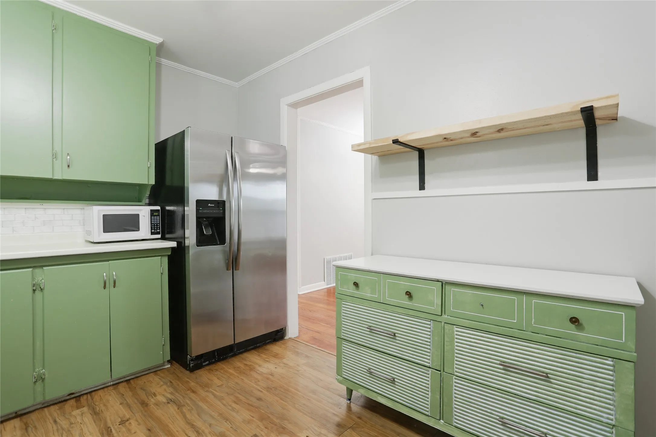 Wood-finish flooring with light green cabinetry