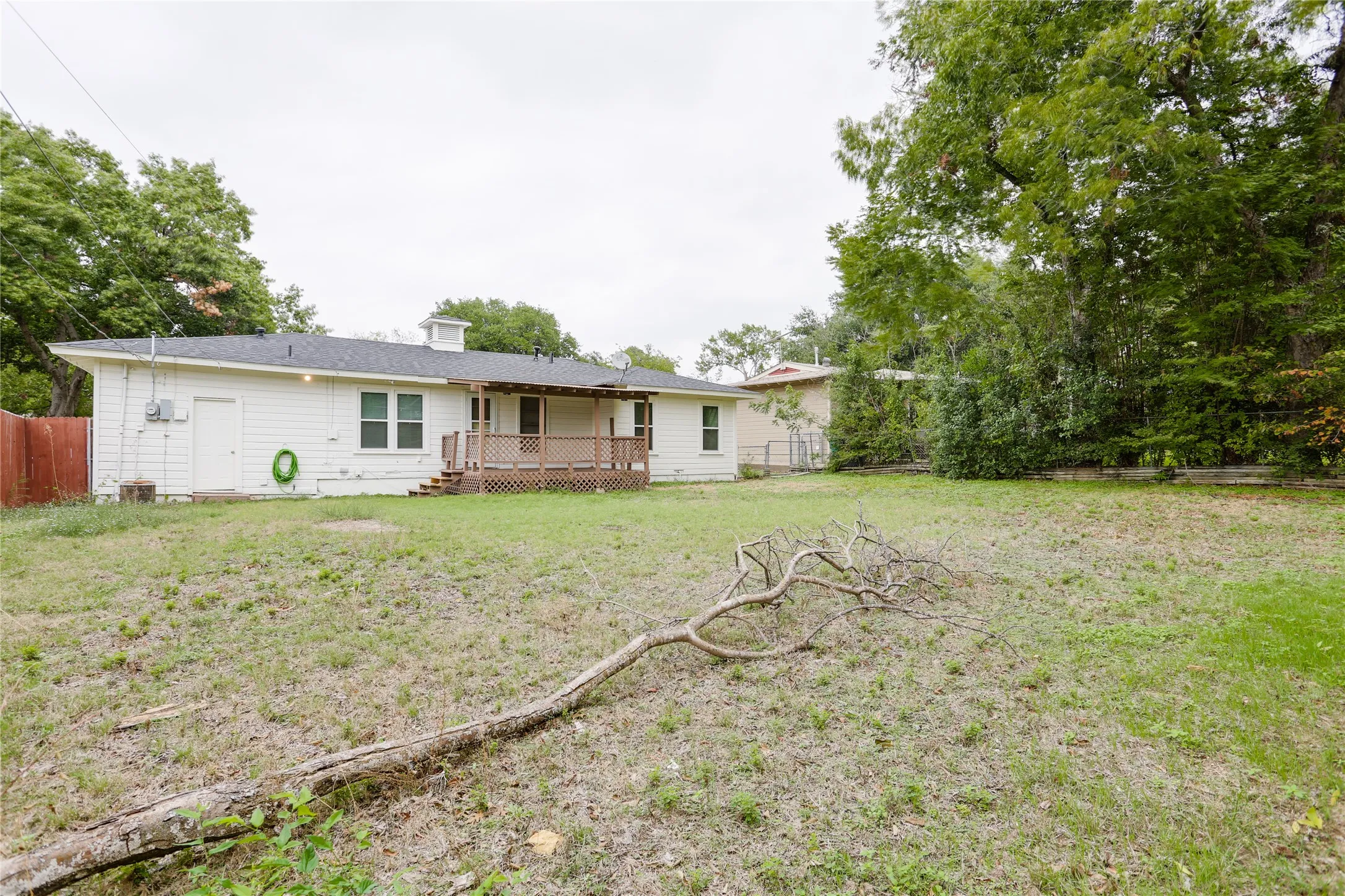 Spacious backyard with mature perimeter trees, a wood-finish fence, and an elevated wood deck