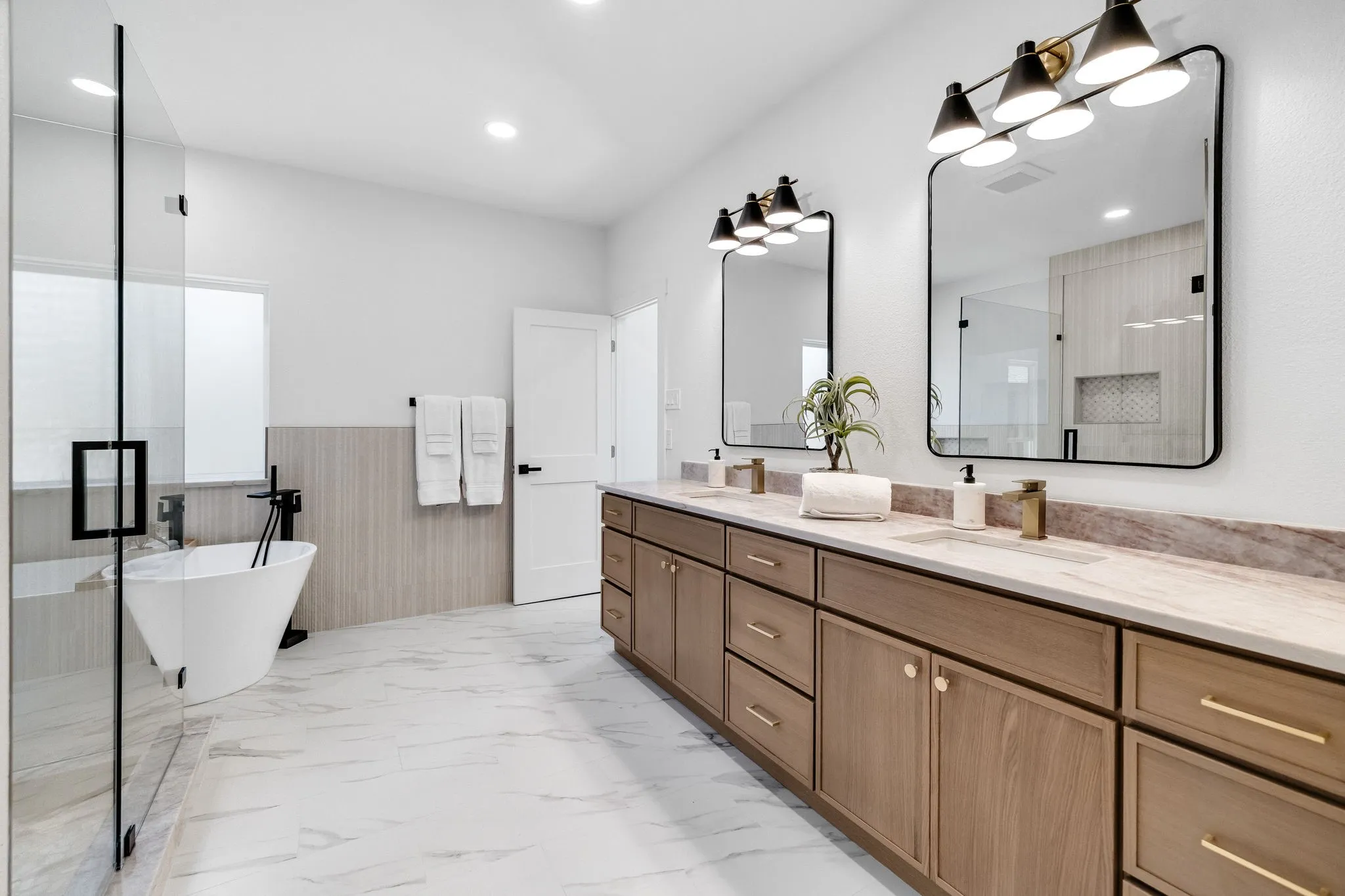 4402 Briargrove-Dual vanity featuring warm wood cabinetry, rectangular sinks, and elegant gold-tone fixtures.