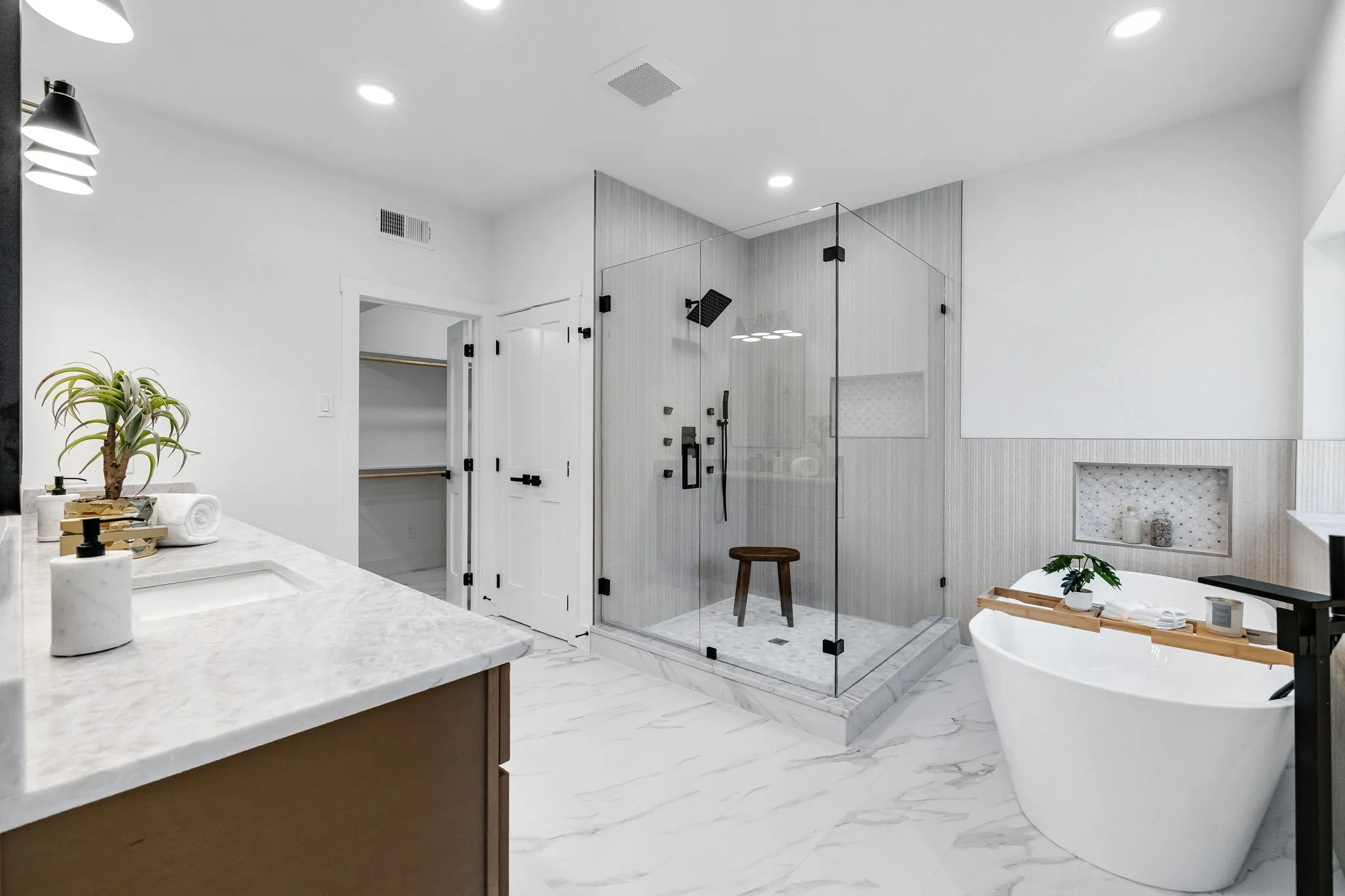 4402 Briargrove-Spa-inspired primary bath featuring a glass-enclosed shower with multiple sprayers, freestanding soaking tub, and custom vanity topped with Taj quartz.