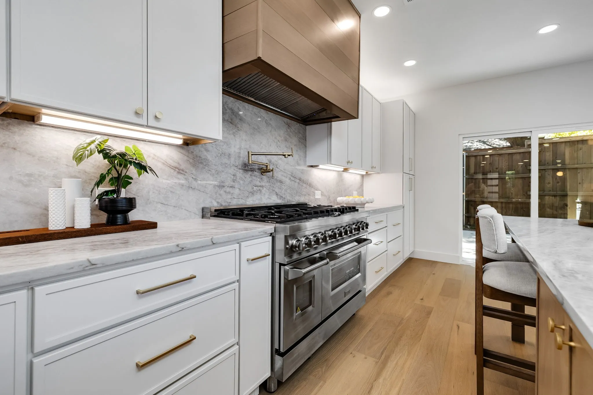 4402 Briargrove-White shaker cabinetry with designer hardware, a 48-inch stainless steel range, and a custom statement range hood.