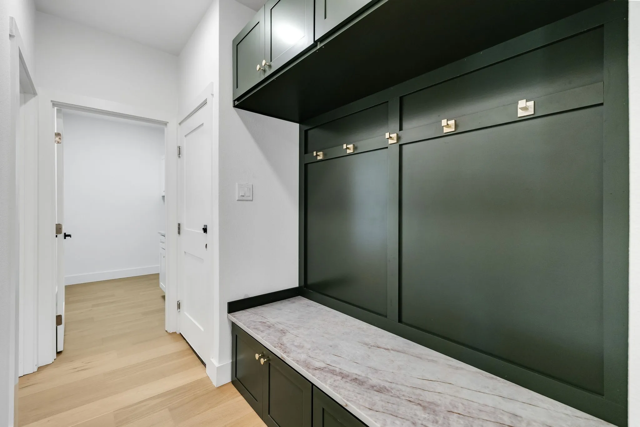 4402 Briargrove-built-in hall storage featuring rich green cabinetry, gold-tone hardware, and a Taj quartz bench top.