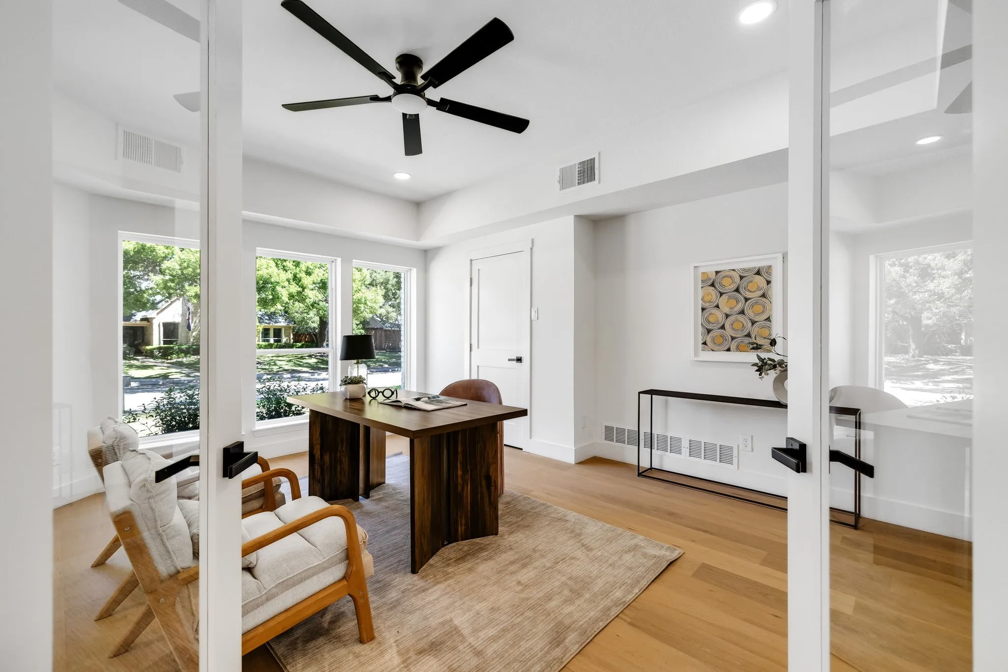 4402 Briargrove-Recessed lighting, wide-plank white oak flooring, glass French doors, a modern ceiling fan, and expansive windows.