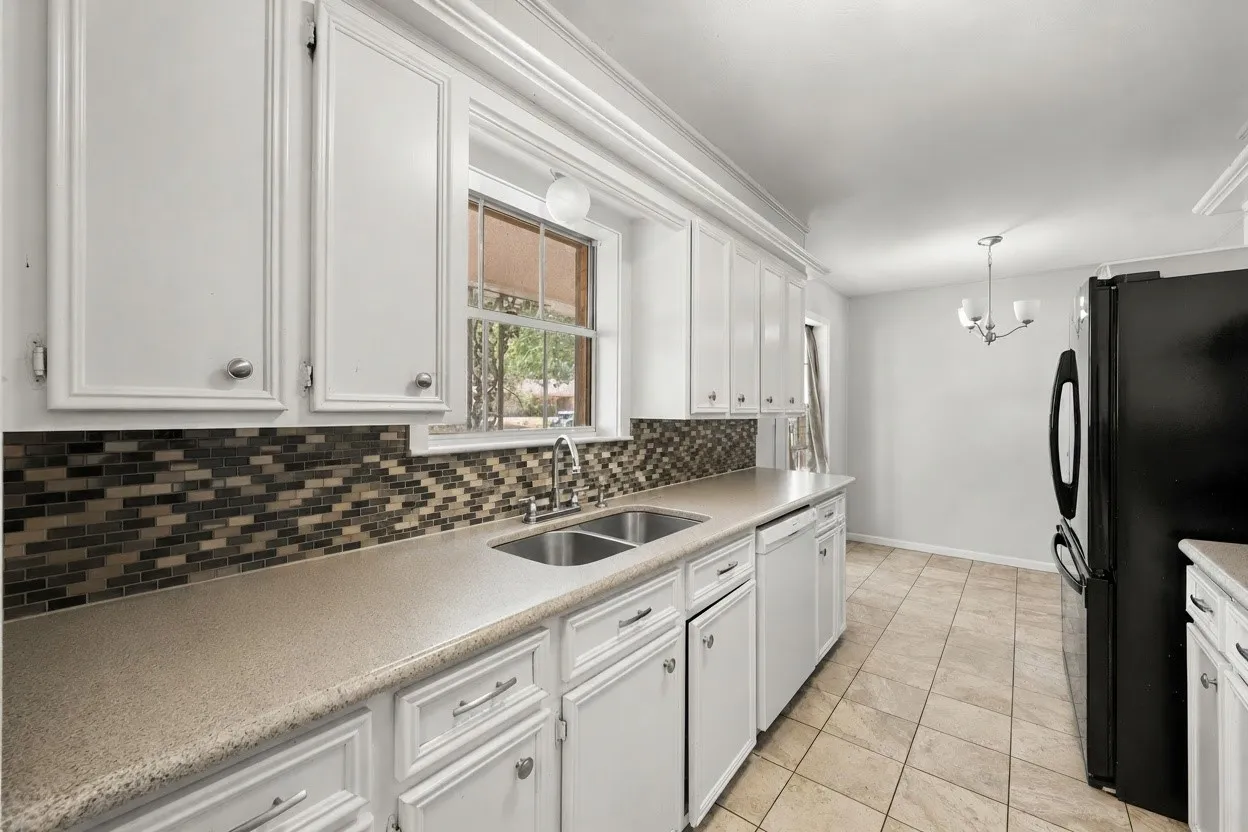 Bright galley kitchen offers generous counter and cabinet space, a double sink, dishwasher, and practical layout designed for everyday living.