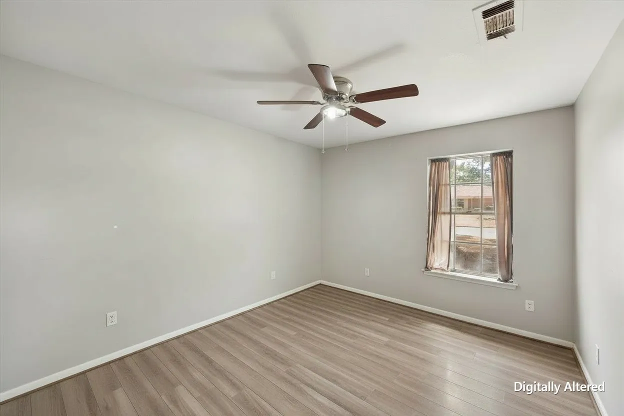 Empty secondary bedroom highlights hard-surface flooring, neutral walls, ceiling fan, and natural light for a versatile rental-friendly space.