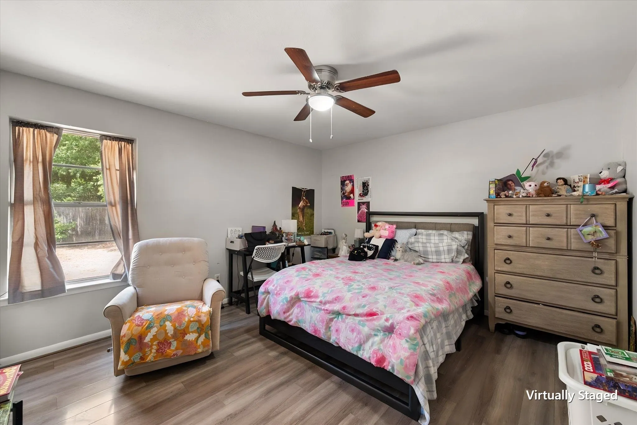 Primary bedroom offers comfortable proportions, hard-surface flooring, natural light, ceiling fan, and access to a private ensuite bathroom.