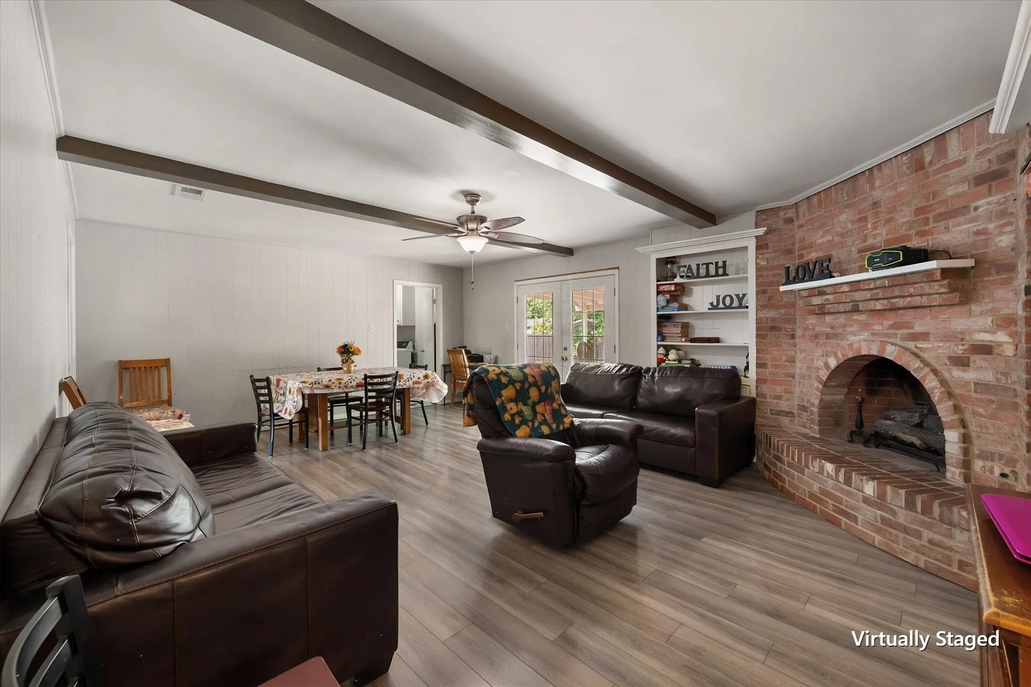 Large living room centers around a classic brick wood-burning fireplace with built-in shelving and plenty of space for comfortable seating.
