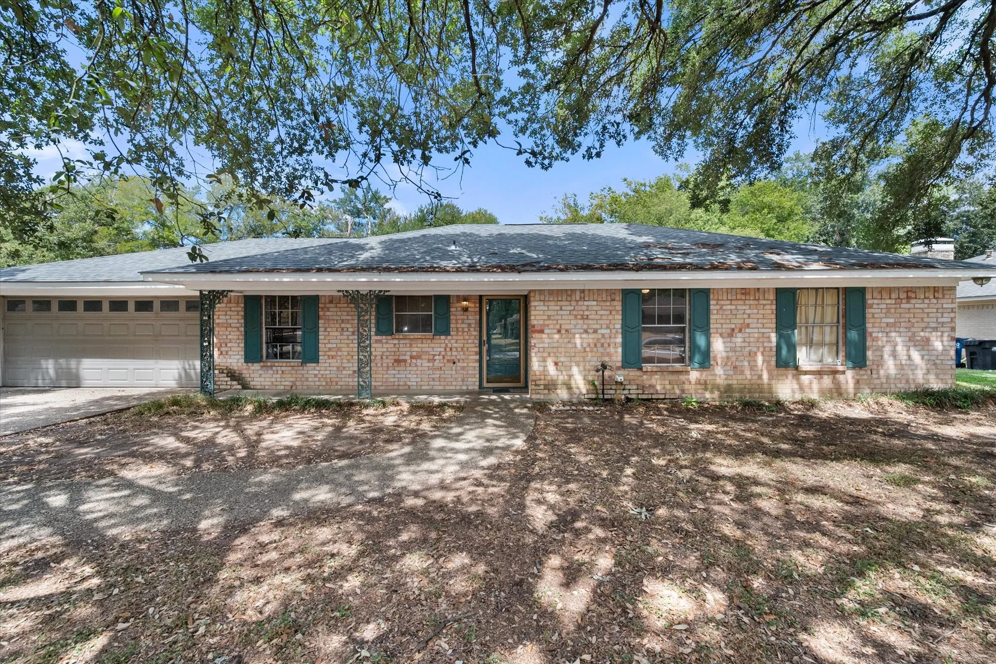 Wide front view of the 3-bedroom Corsicana rental property showcases its traditional brick exterior, mature trees, and inviting residential setting in Navarro County.