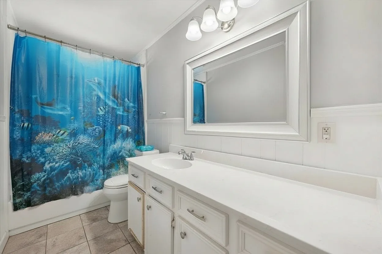 Full secondary bathroom features a spacious vanity, built-in cabinetry, bright finishes, and a shower-tub area for everyday convenience.