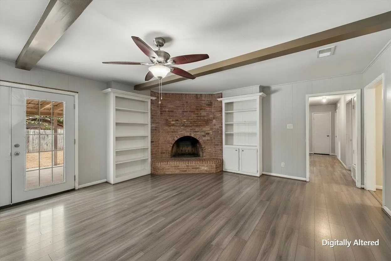 Unfurnished living room view showcases the wood-burning brick fireplace, built-in shelving, and generous floor space in this Corsicana rental property.