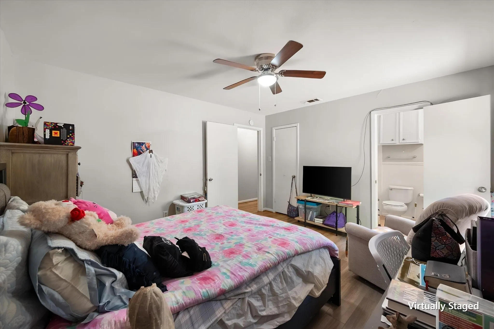 Alternate primary bedroom view shows the room's functional layout, ceiling fan, closet access, and connection to the ensuite bath.