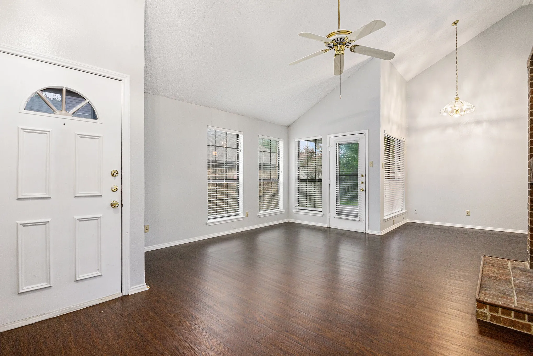 Vaulted ceiling with a ceiling fan, dark wood-finish flooring, and multiple windows with blinds