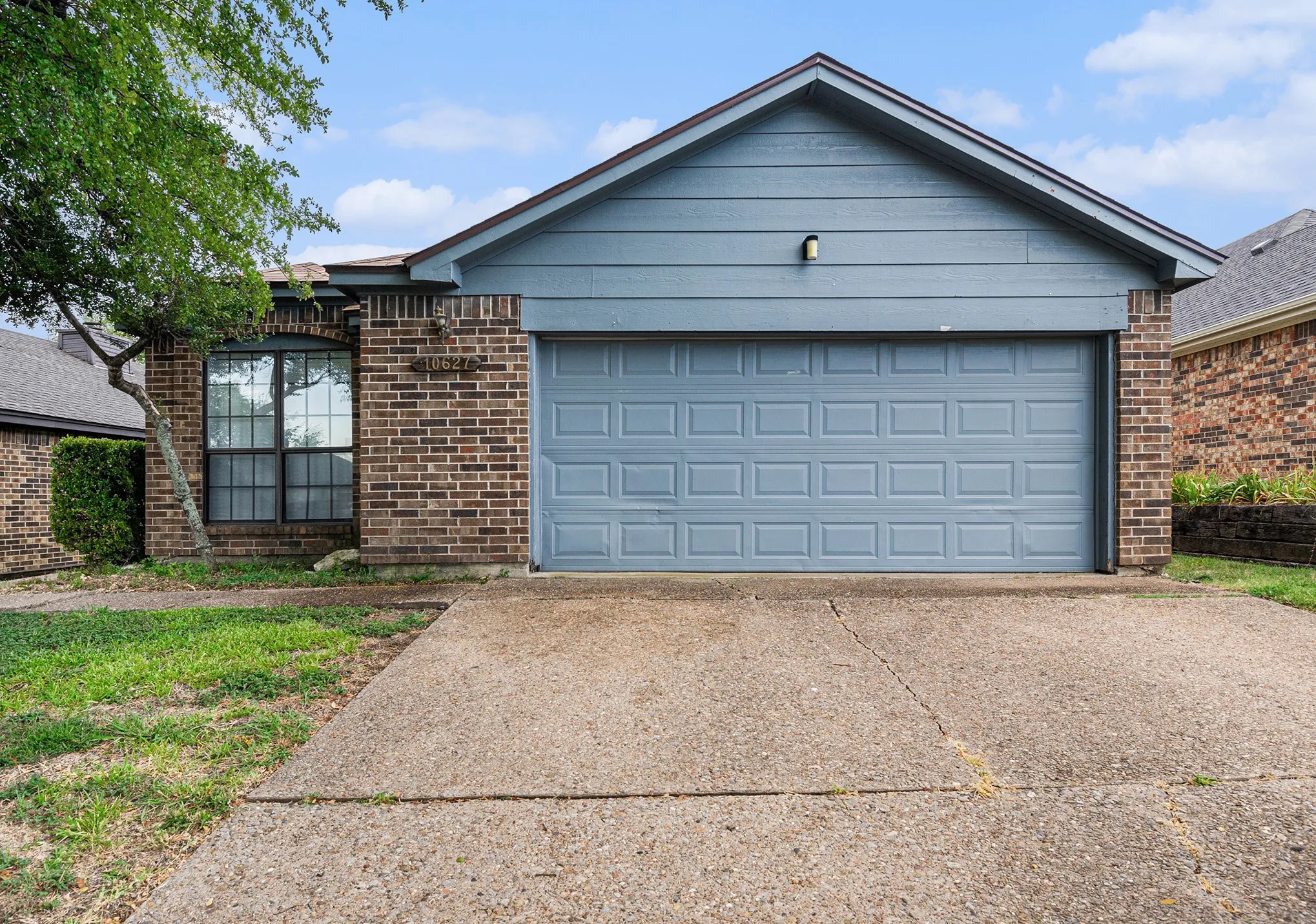Brick and siding exterior with an attached two-car garage, concrete driveway, and front-facing window