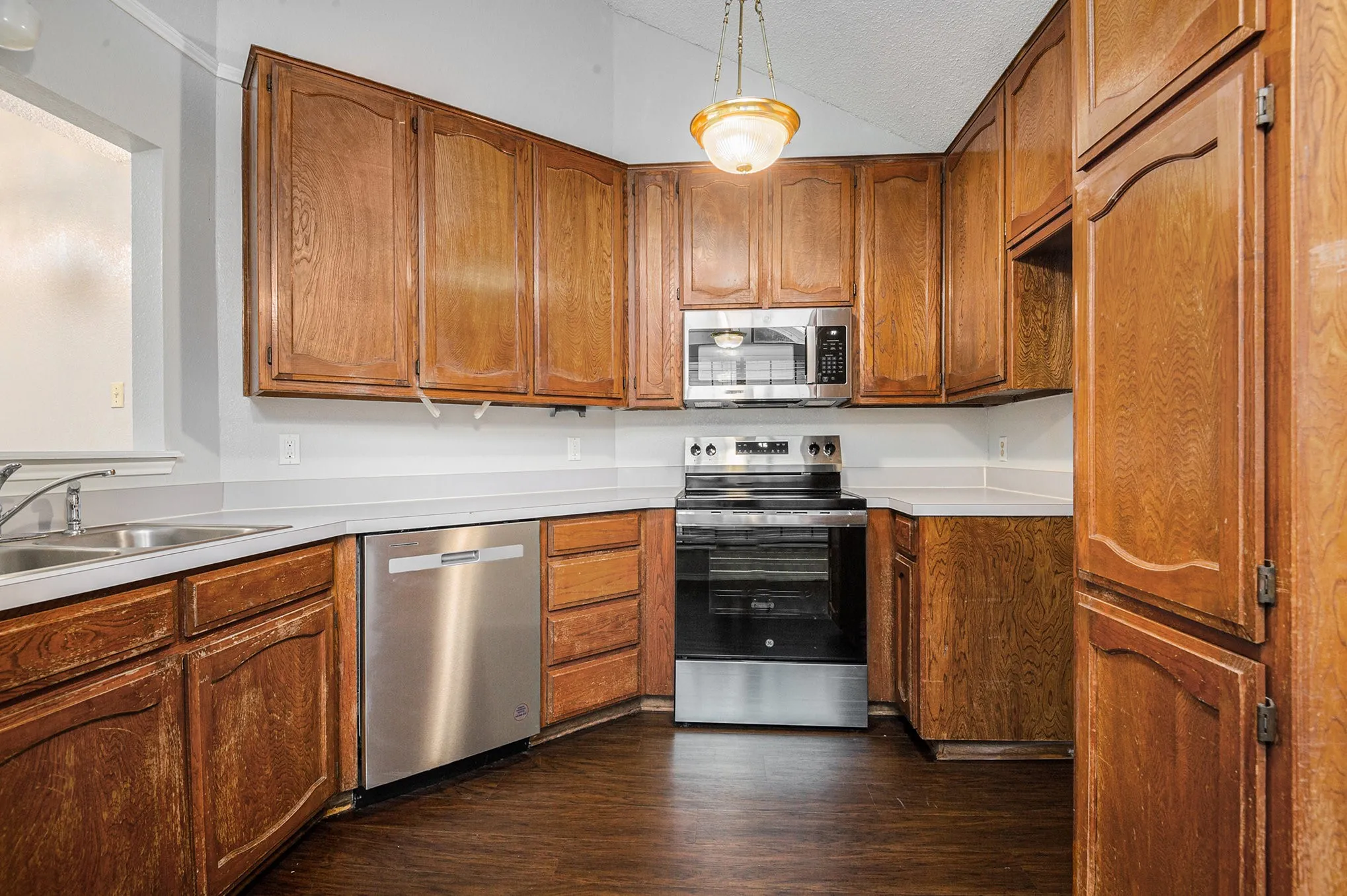 Kitchen featuring wood-finish cabinetry, white countertops, a stainless steel dishwasher, a stainless steel range, and a stainless steel microwave