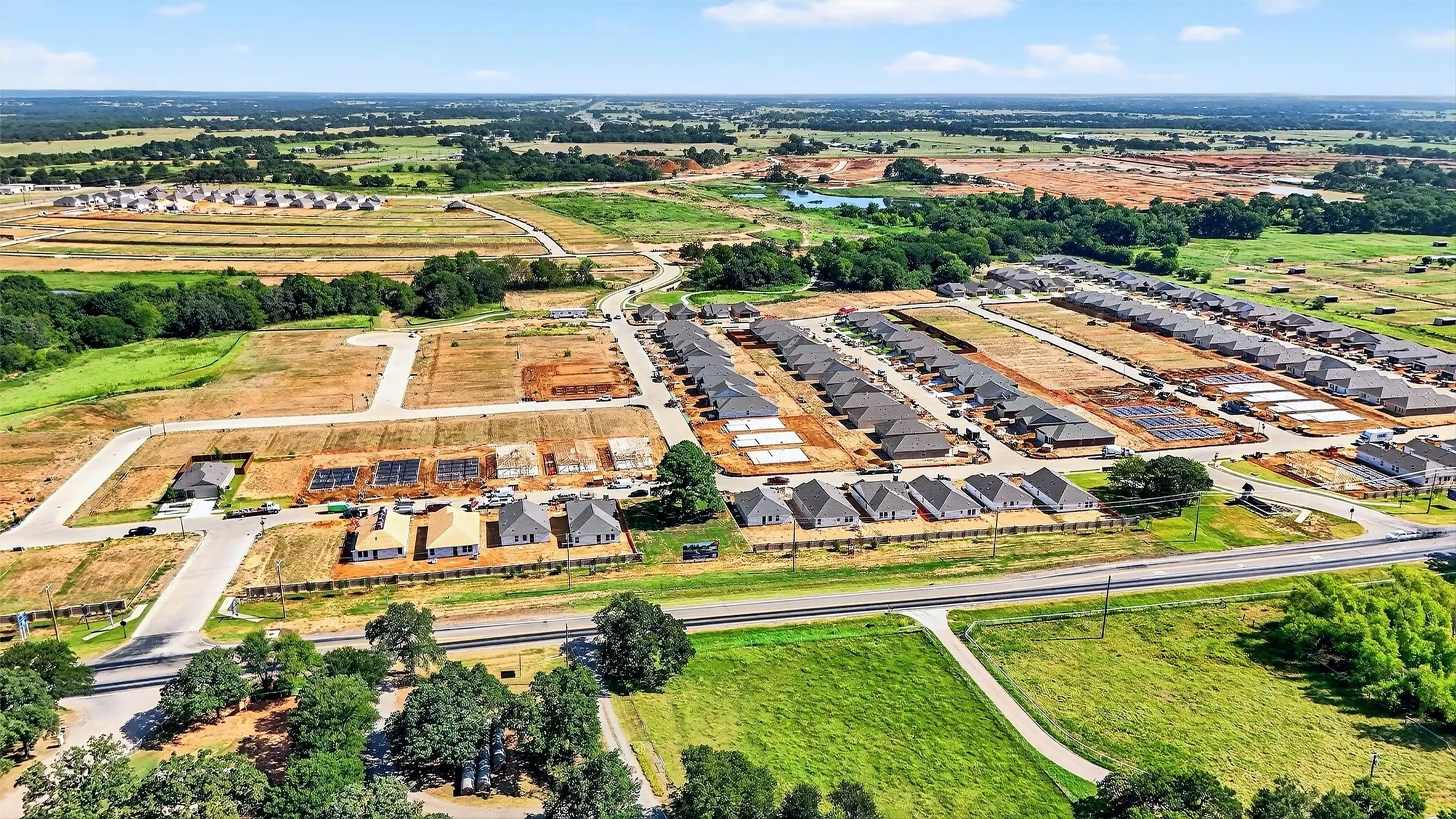 Aerial perspective of a developing residential community, featuring multiple new construction homes with dark gray roofing and light-colored facades