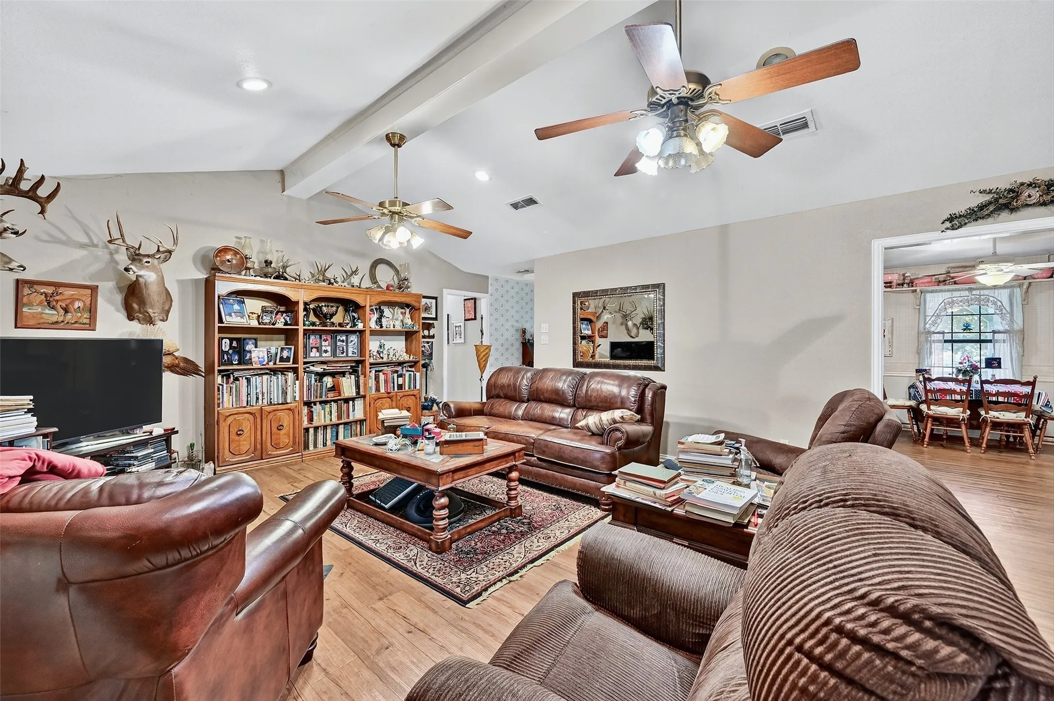 Vaulted ceiling with exposed beams, recessed lighting, wood-finish flooring, and built-in shelving