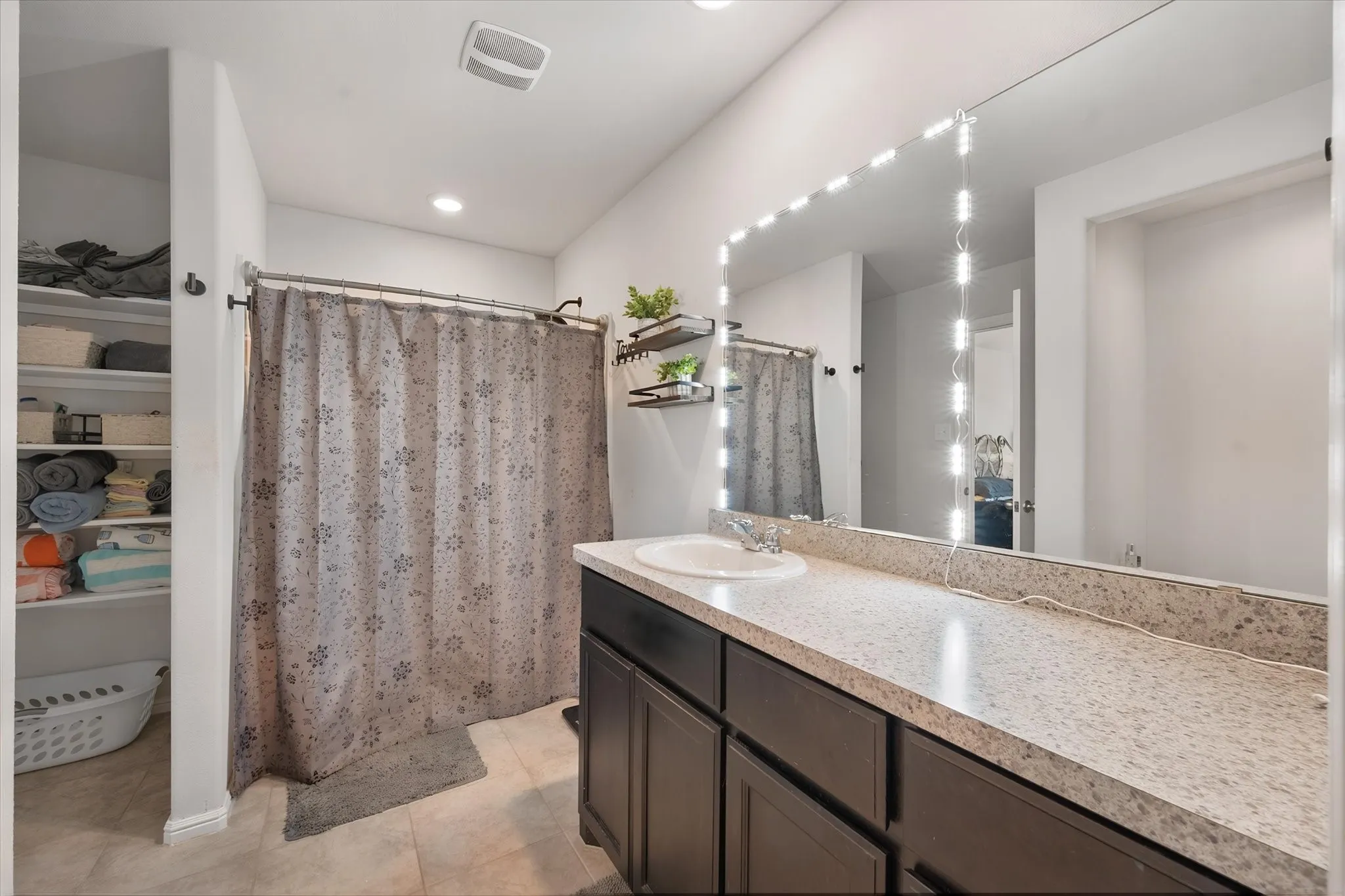 Extended vanity with a built-in sink, dark wood-finish cabinetry, and a large wall-mounted mirror