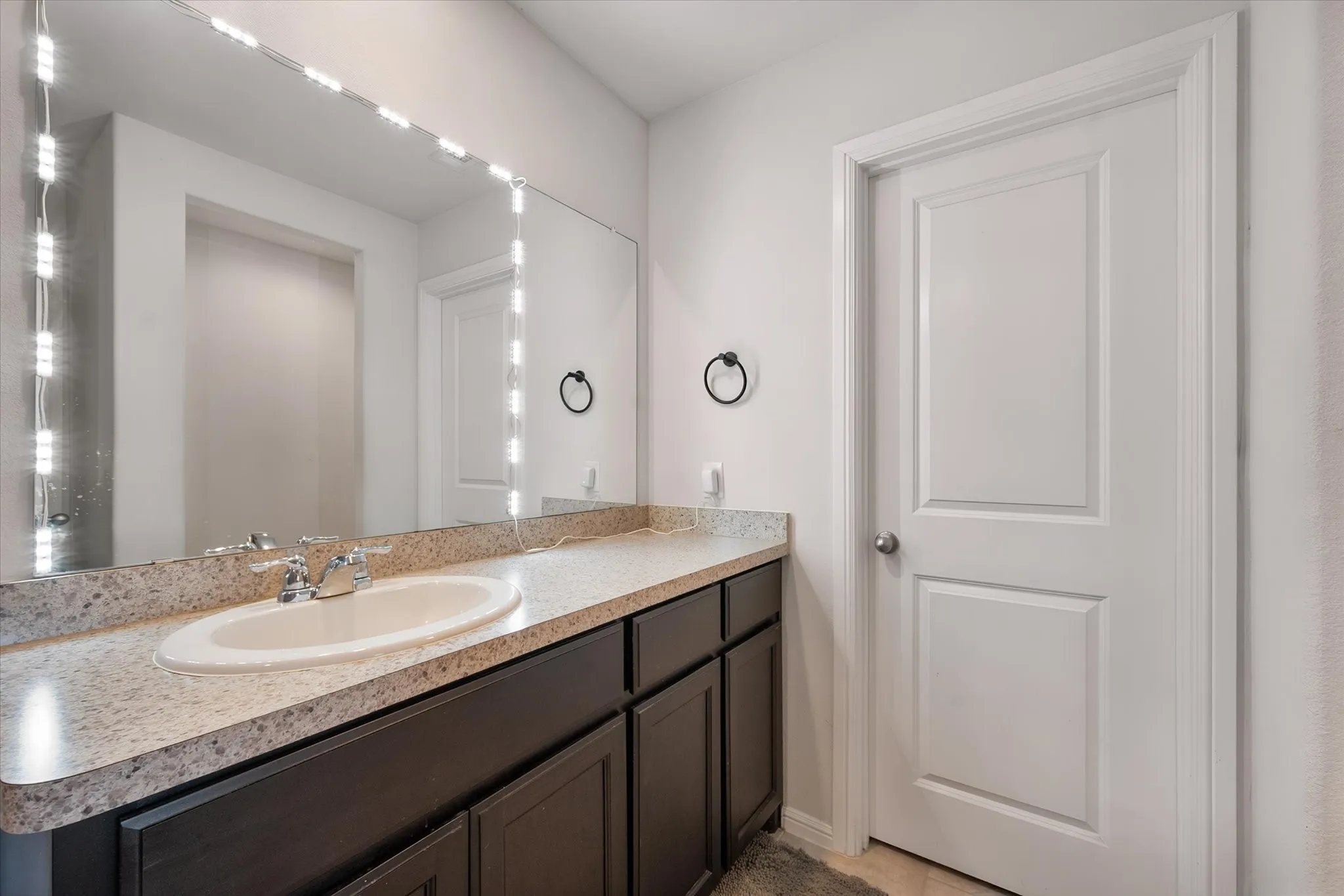Vanity with an integrated sink, polished chrome faucet, and dark wood-finish cabinetry