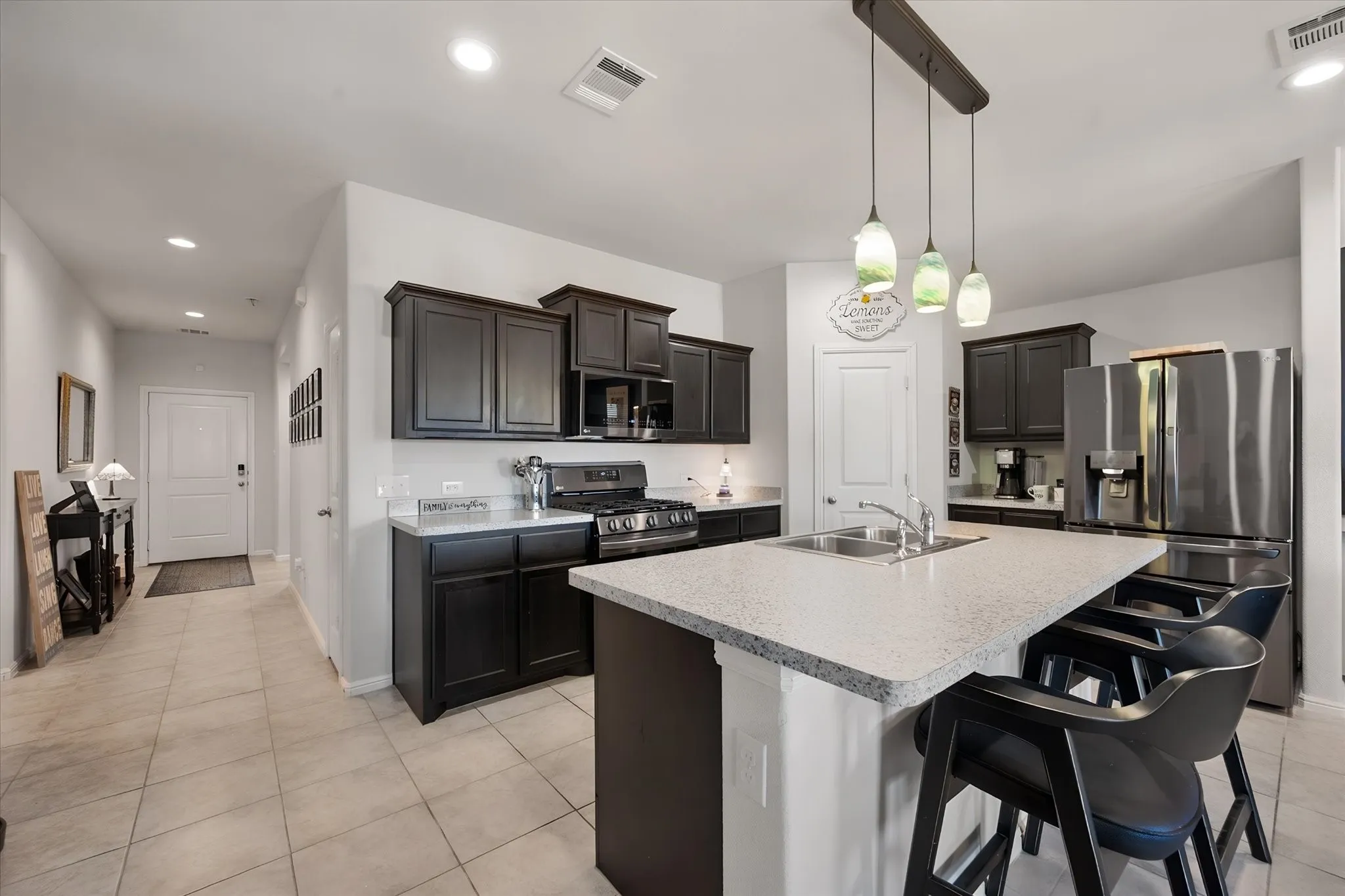Kitchen featuring dark wood cabinetry, light-toned countertops, dark stainless steel appliances and tile flooring