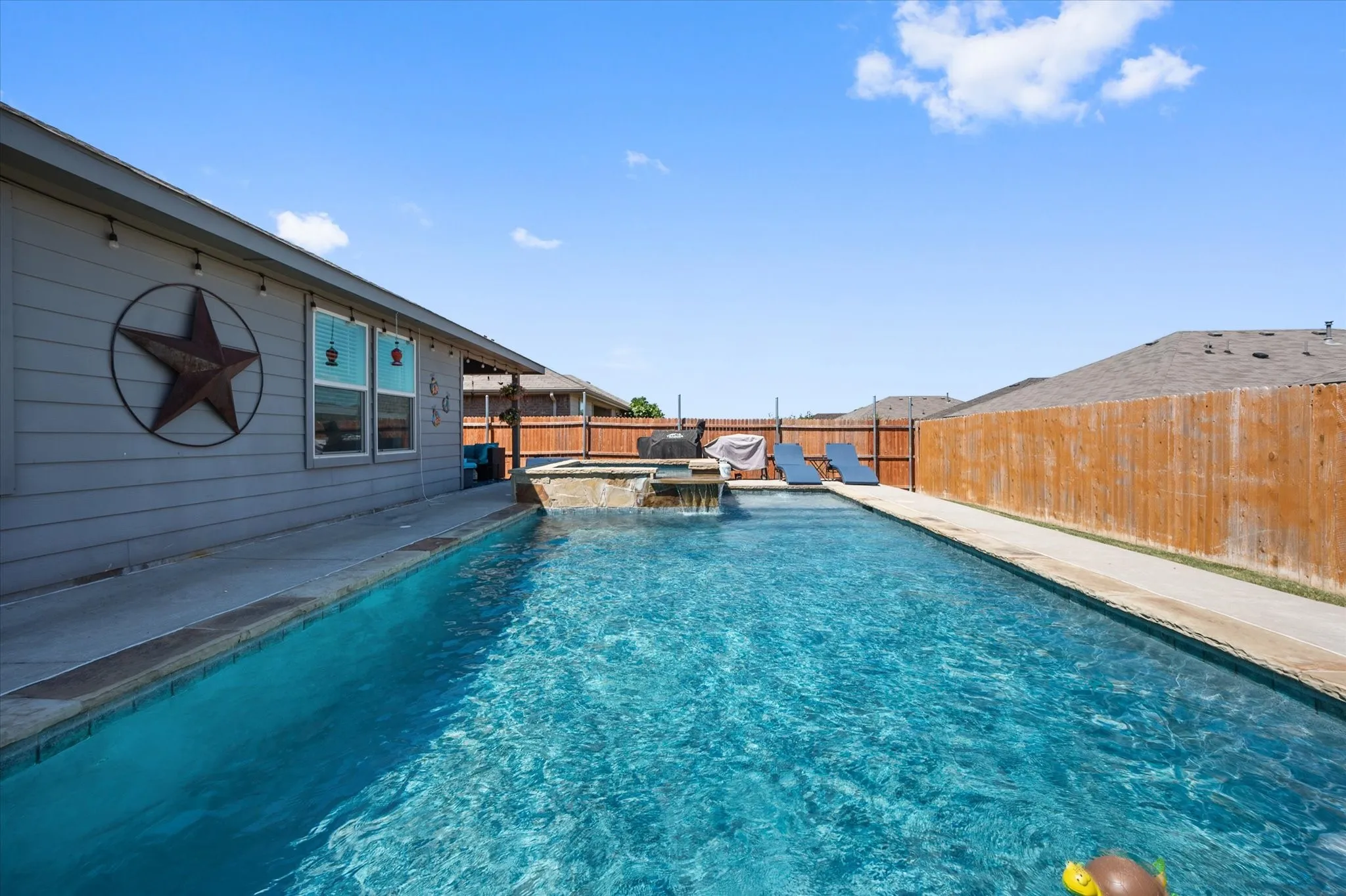 Backyard featuring a rectangular swimming pool, integrated spa, and concrete pool decking