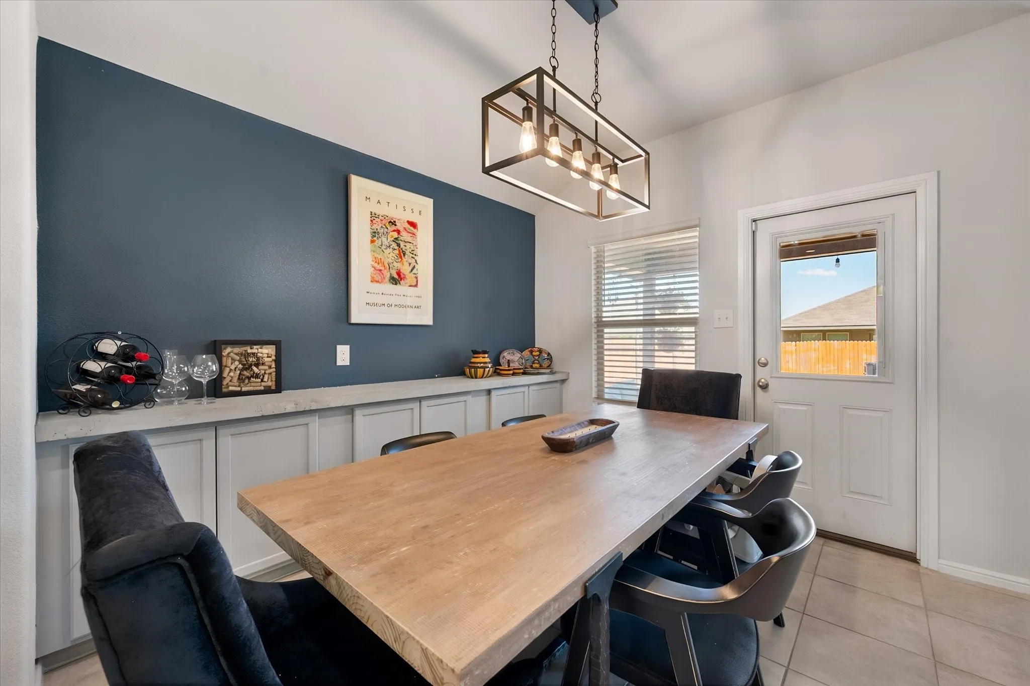 Rectangular multi-bulb chandelier, built-in lower cabinetry with solid surface concrete counter-top, accent wall and a rear exterior door leading to the covered patio!