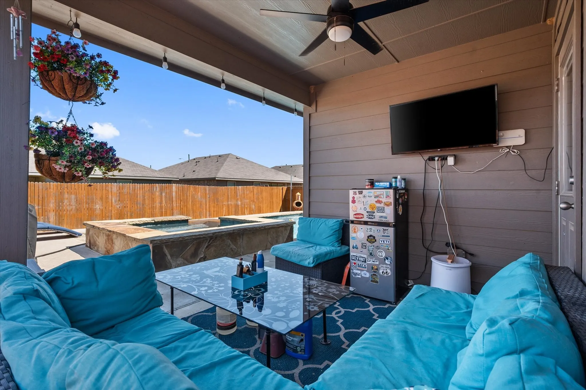 Covered patio featuring a ceiling fan, wall-mounted television overlooking the pool and spa!