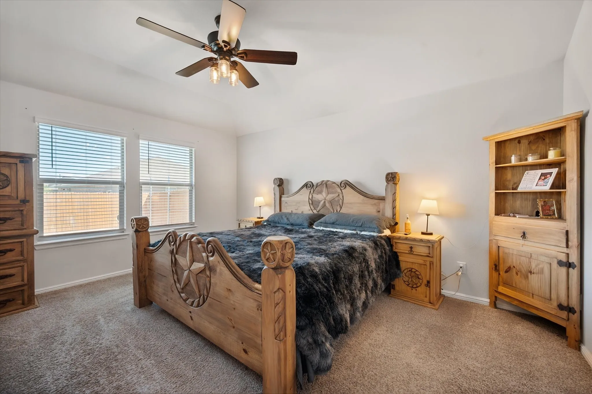 Carpeted flooring, vaulted ceiling, dual windows with blinds, and an overhead ceiling fan