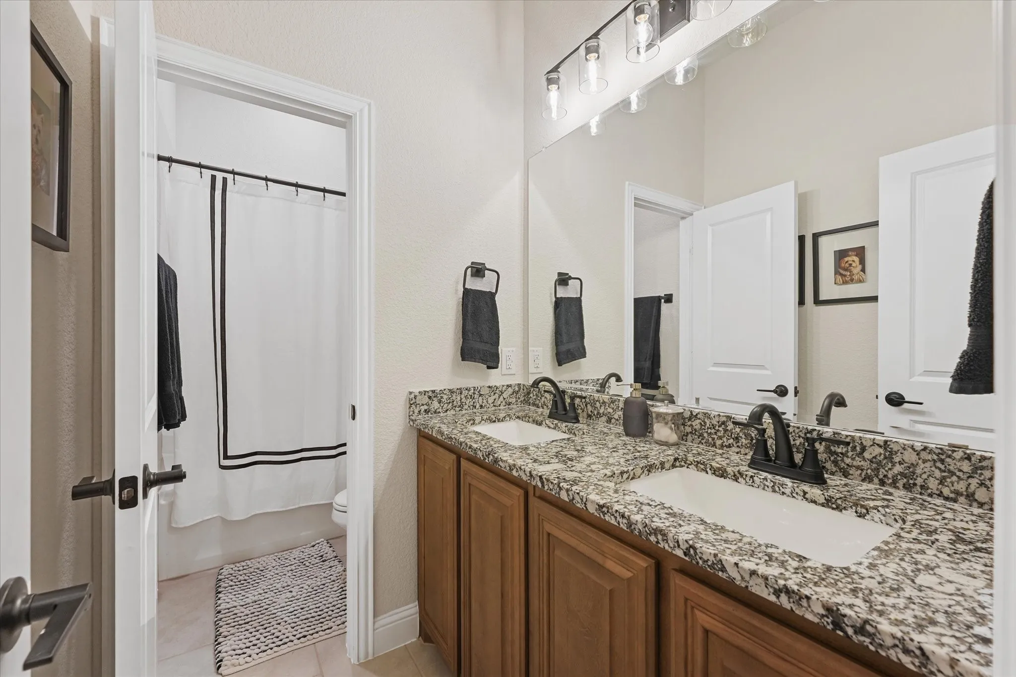 Full downstairs bathroom with dual sinks, granite countertops, generous vanity storage, and separate tub and shower area—conveniently located near the secondary bedrooms.