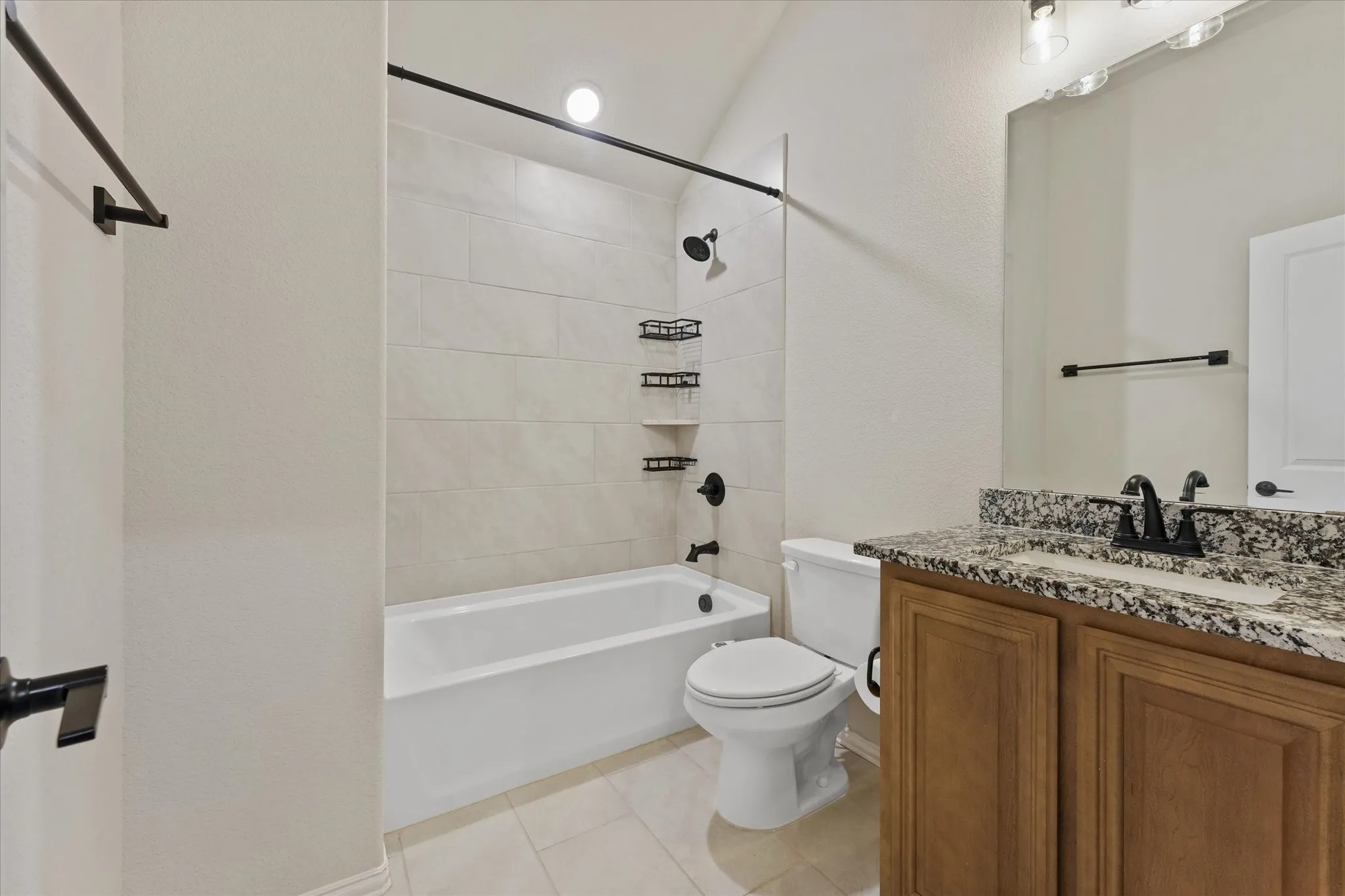 Upstairs full bathroom with granite countertop, tub and shower combination with tile surround, and black fixtures.