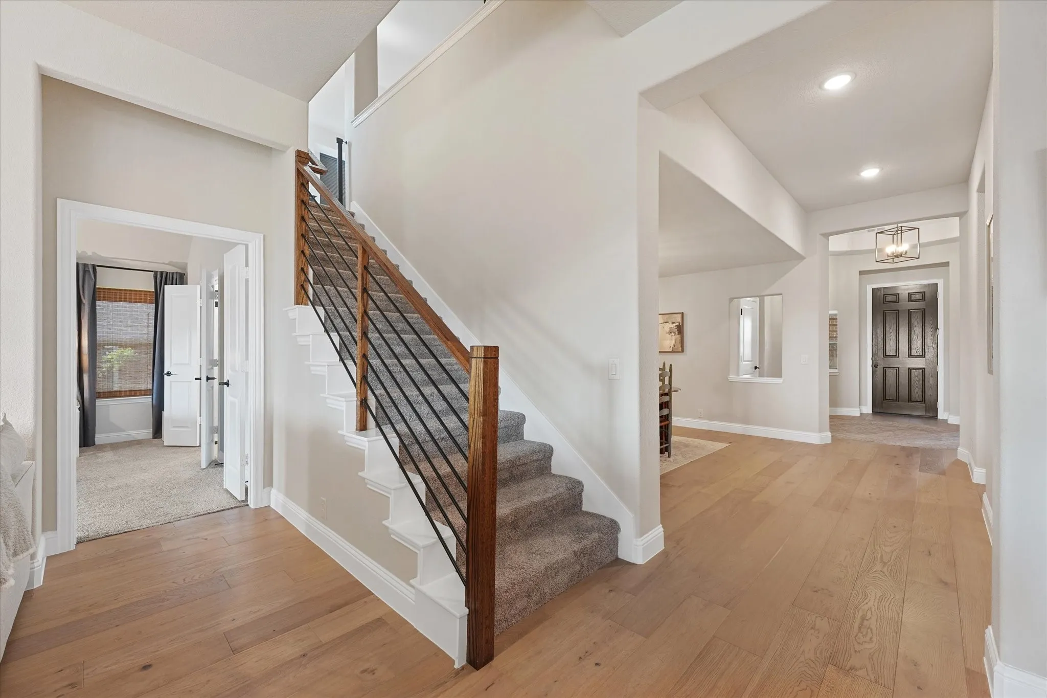 Engineered hardwood floors continue through the main level with an upgraded open staircase featuring wood railing and horizontal iron balusters. The Carolina III layout includes three bedrooms downstairs plus additional living space upstairs.
