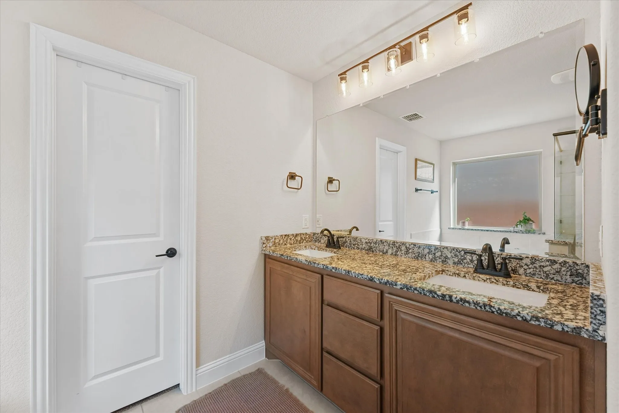 Primary bathroom features dual sinks, granite countertops, large vanity, extensive mirror, and separate bathing and shower areas.