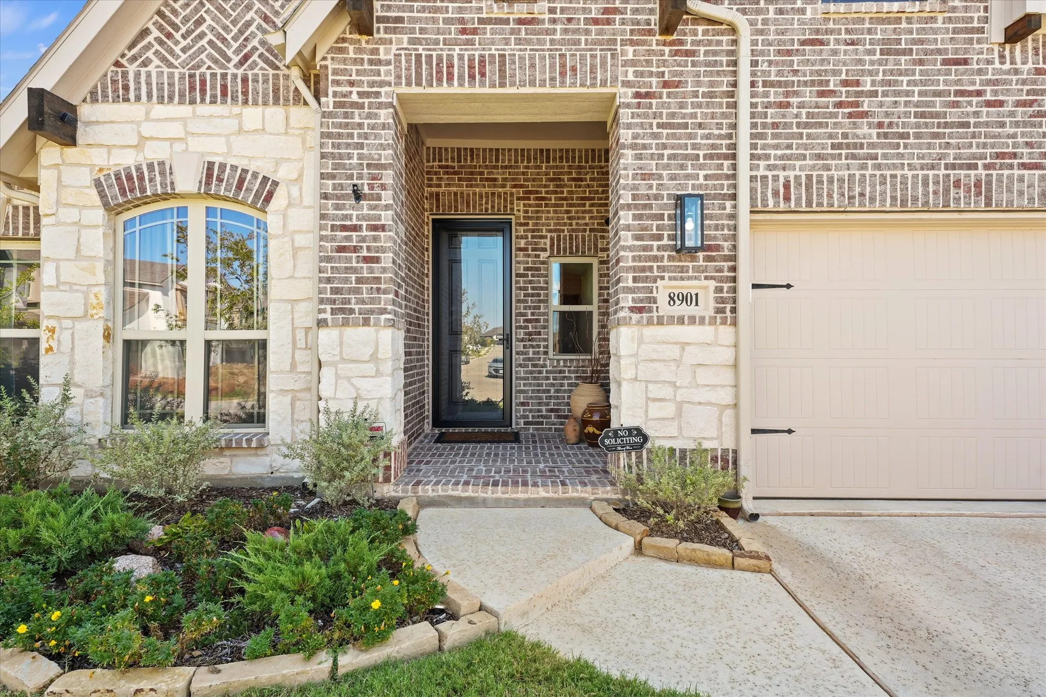Covered brick front porch with stone accents and glass storm door. The upgraded exterior elevation and established landscaping give this newer Country Lakes home a finished, move-in-ready appearance.