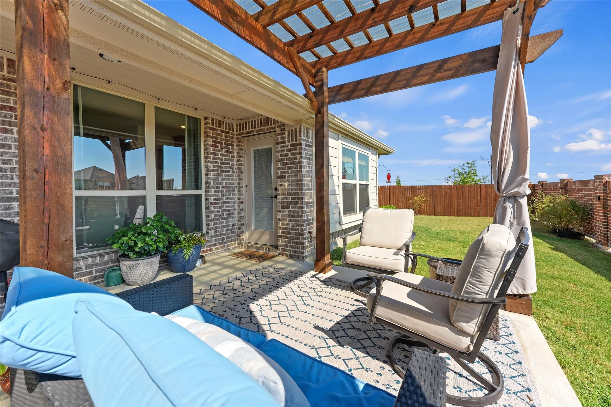 Closer view of the pergola-covered patio with room for multiple seating areas and direct access to the home and backyard.