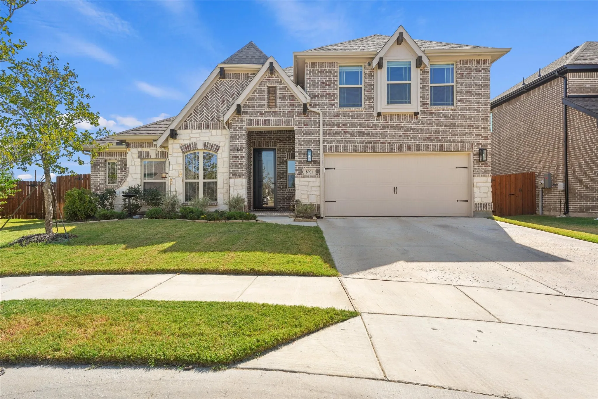 Front view of this 4-bedroom Country Lakes home featuring brick and stone construction, upgraded architectural elevation, two-car garage, mature landscaping, and a premium homesite in the Argyle 76226 area.
