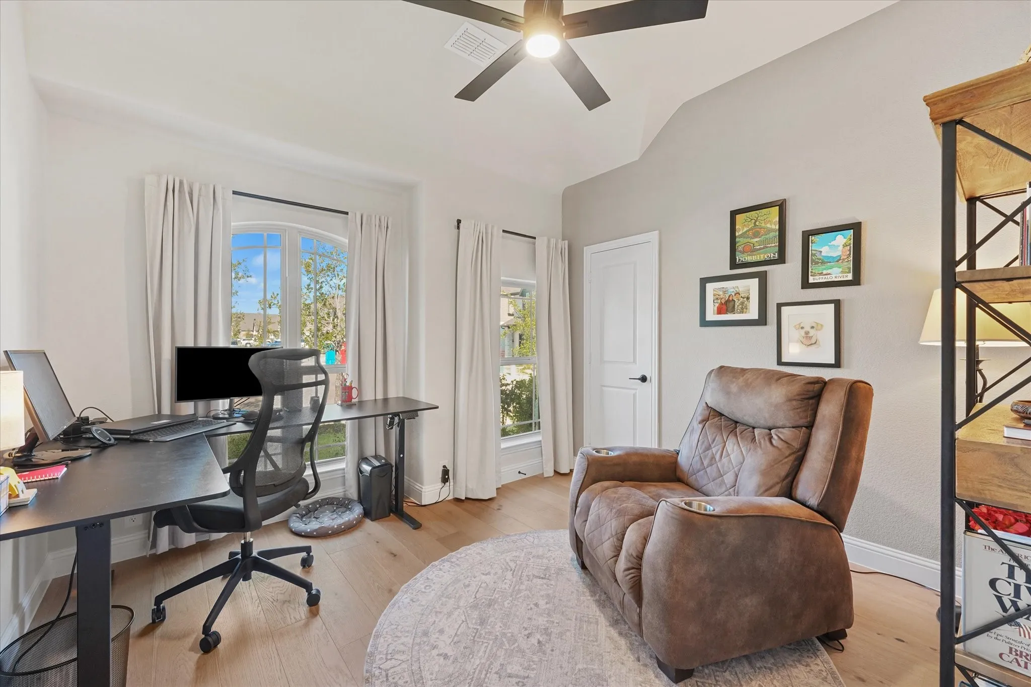 Dedicated first-floor home office with engineered hardwood floors, large windows, vaulted ceiling, and glass doors. The separate study allows this four-bedroom home to keep all four bedrooms available for sleeping space.