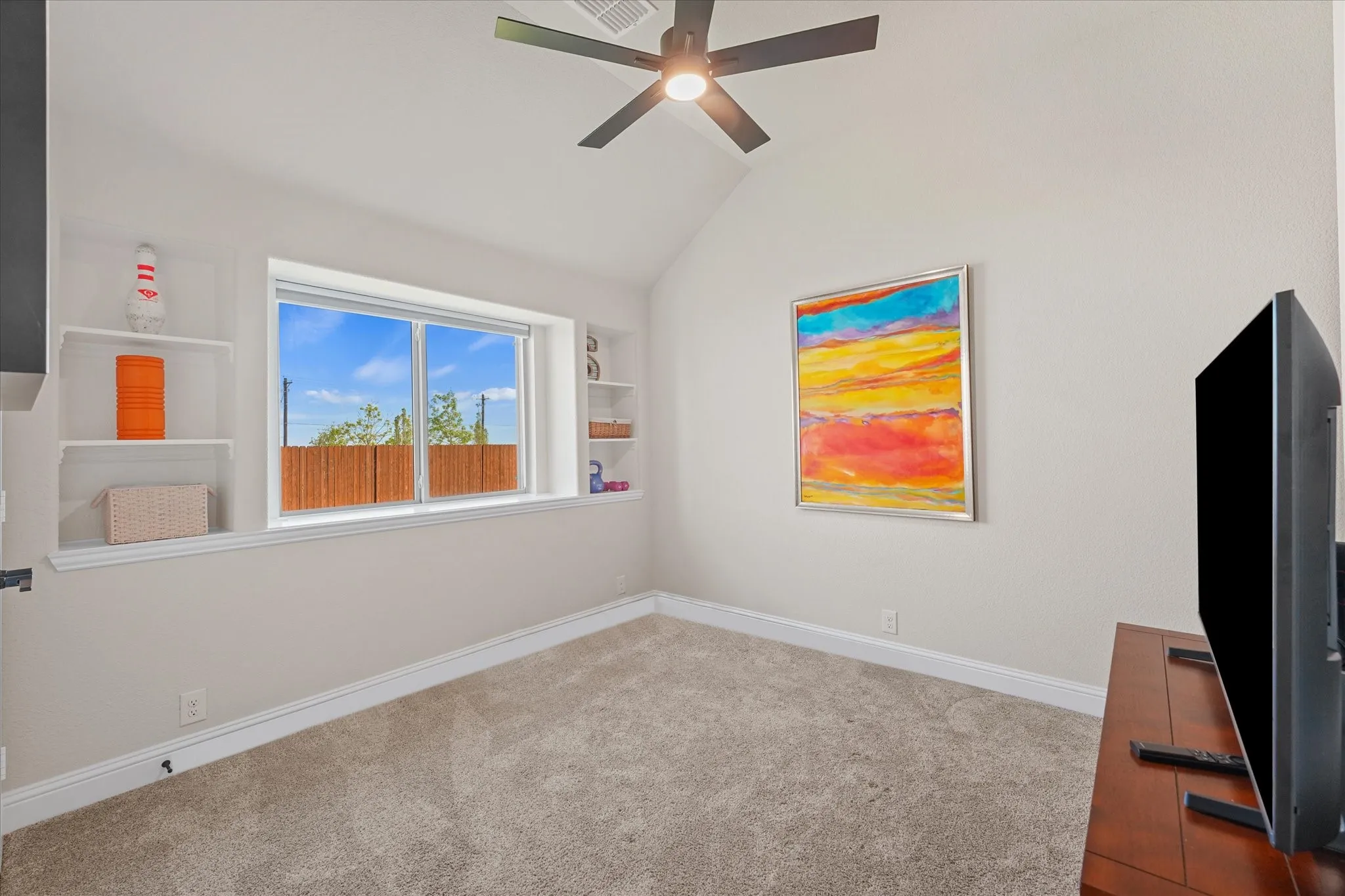 First-floor secondary bedroom with vaulted ceiling, large window, built-in shelving, and walk-in closet. This Carolina III floor plan offers three bedrooms downstairs.