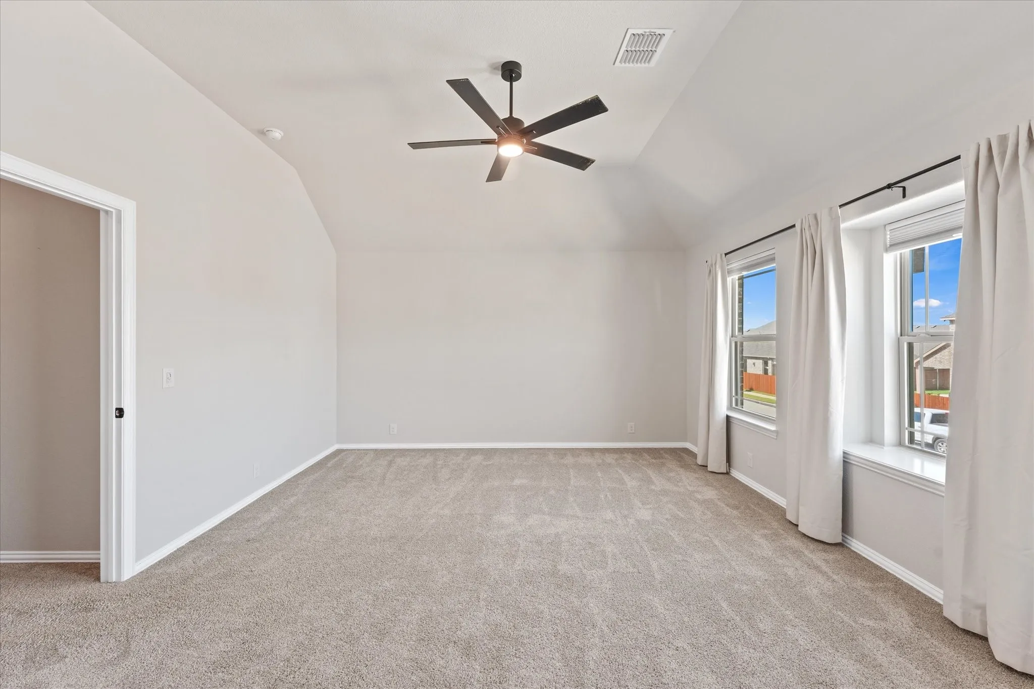 Large upstairs bedroom with vaulted ceiling, ceiling fan, multiple windows, and generous floor space. This room could also work well for guests, a home office, workout space, or additional flex room.
