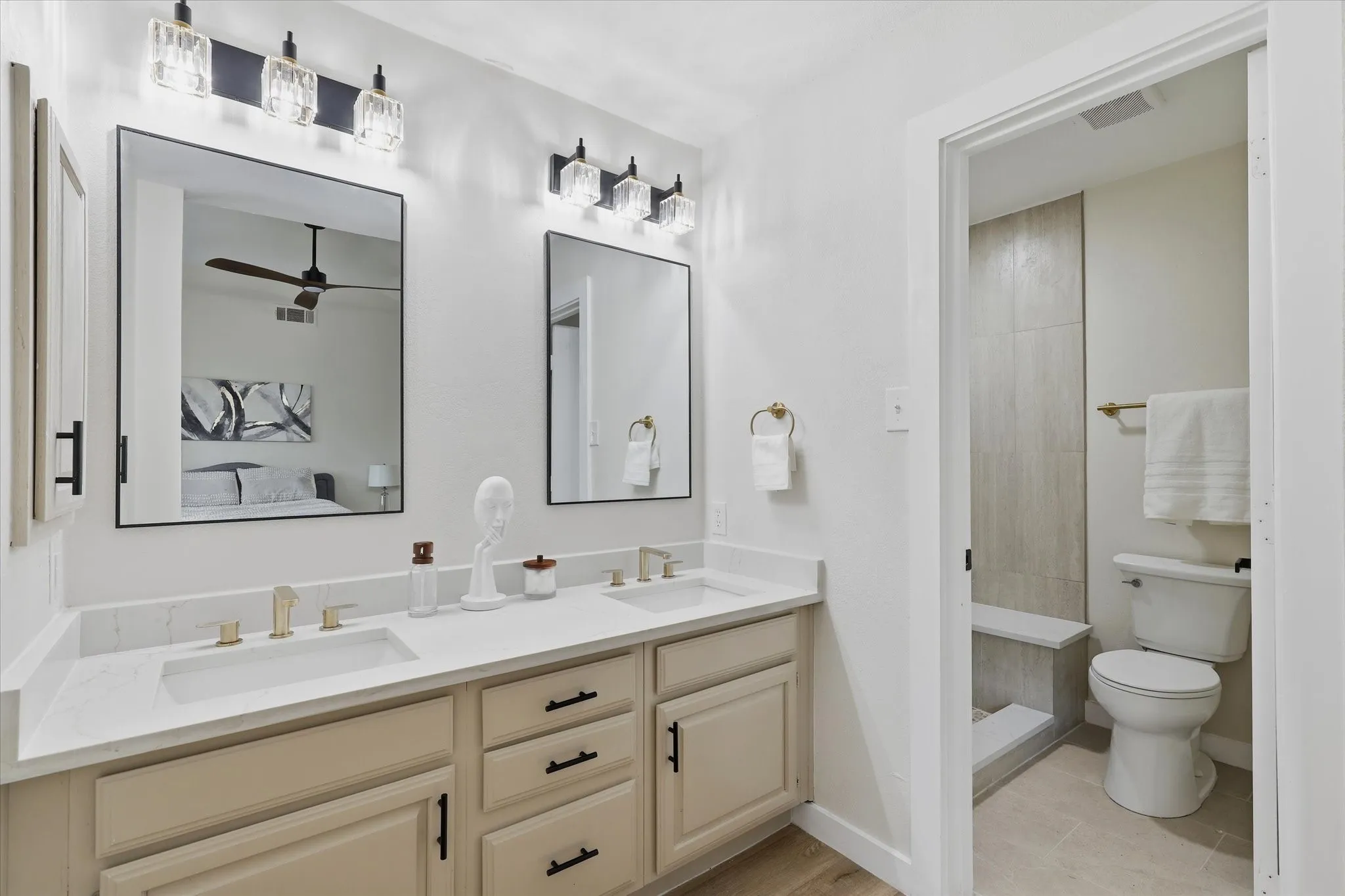 Dual vanity with white countertops, undermount sinks, and gold-finish fixtures