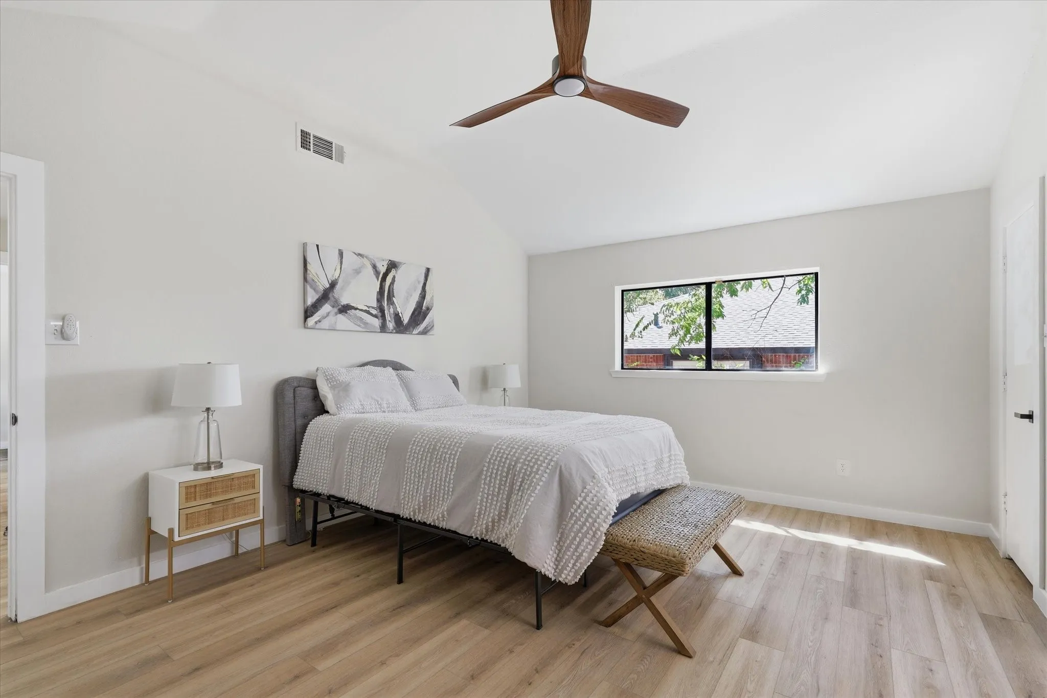 Vaulted ceiling with a wood-finish ceiling fan, wood-finish flooring, and white walls