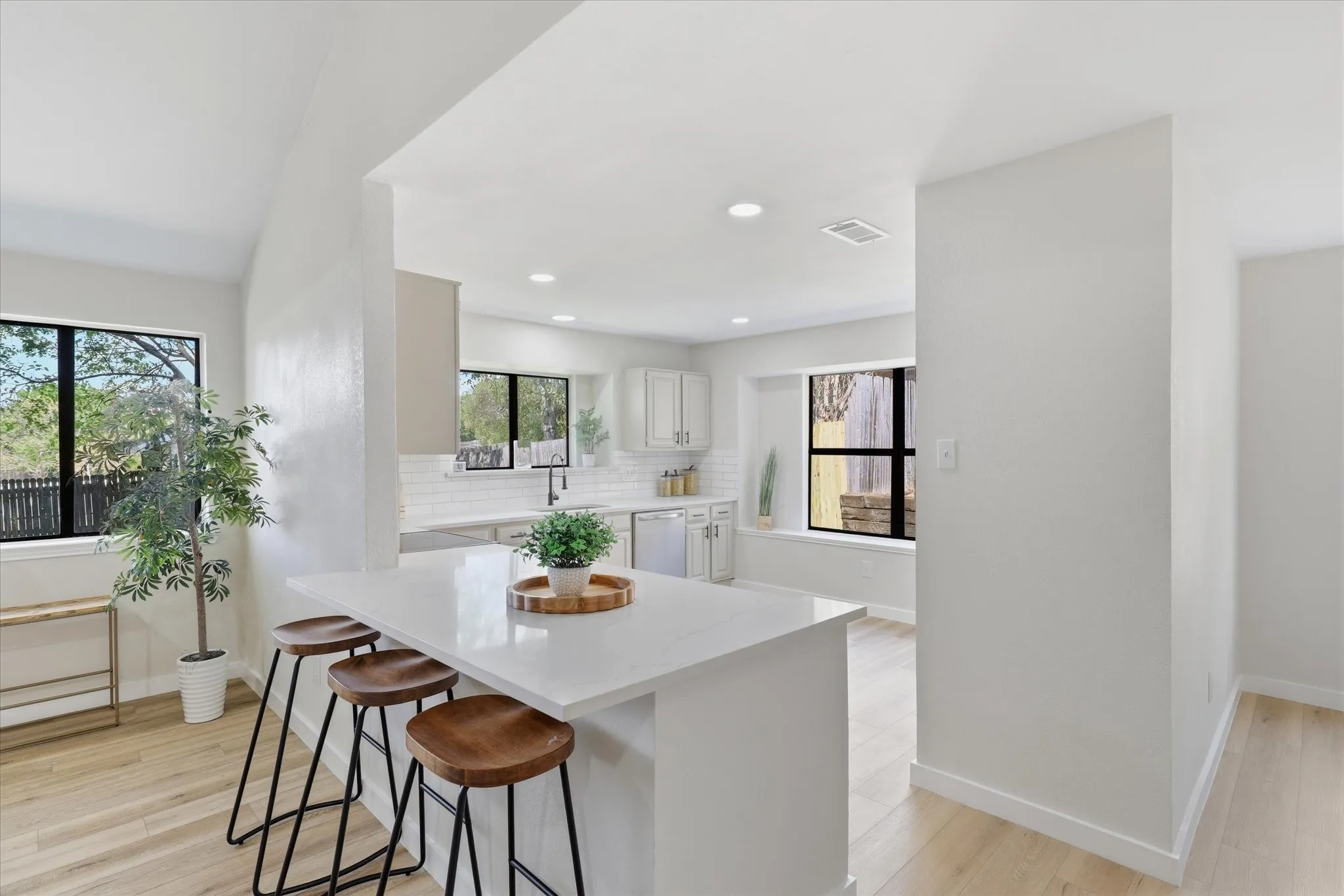 Kitchen featuring a peninsula with a light-toned countertop, subway tile backsplash, white cabinetry, and wood-finish flooring