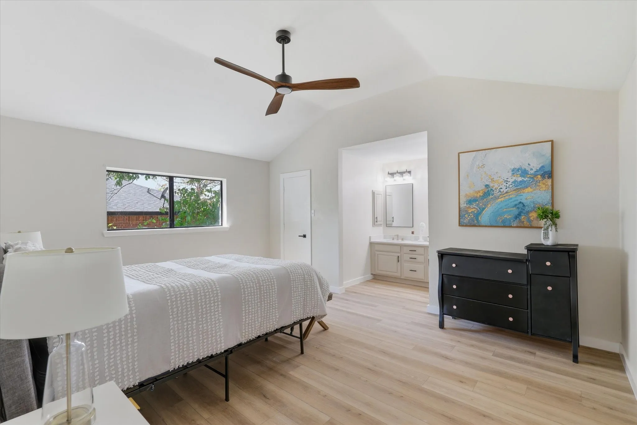 Vaulted ceilings with a ceiling fan, recessed window, wood-finish flooring, and an en-suite vanity with a single sink