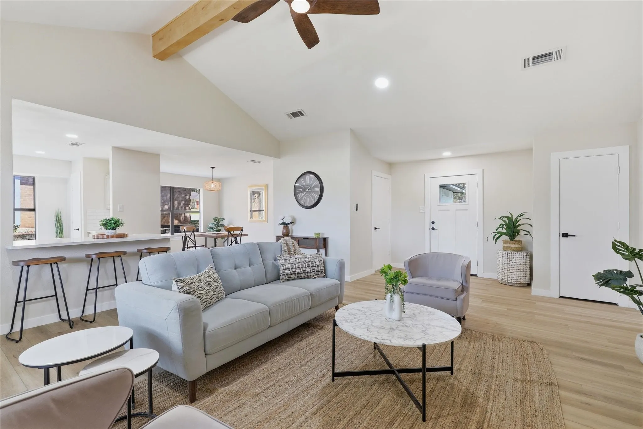 Vaulted ceiling with exposed wood beam, recessed lighting, wood-finish flooring, breakfast bar with seating, and a modern ceiling fan