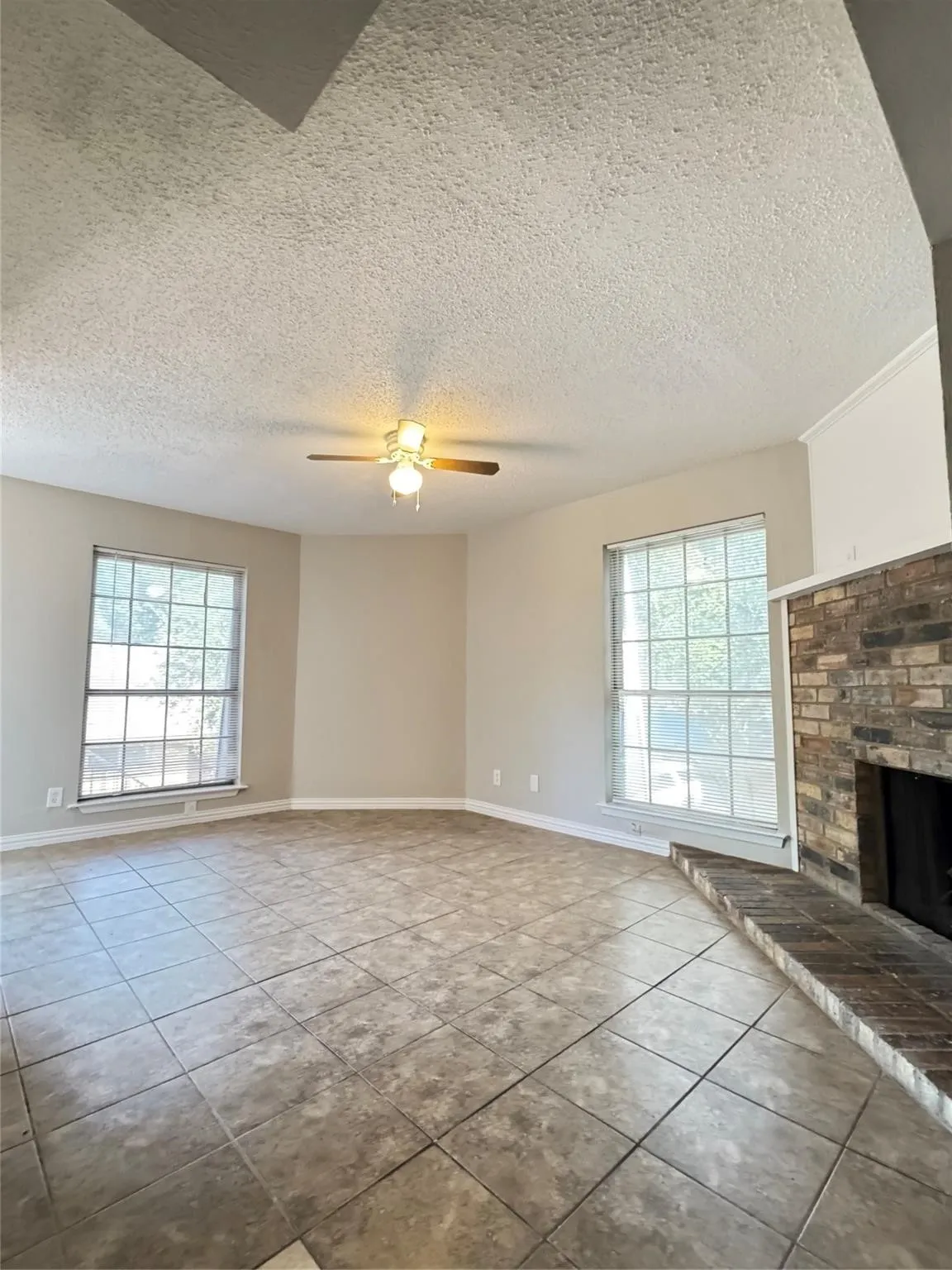 Spacious room featuring neutral wall tones, large windows with white trim, and a ceiling fan