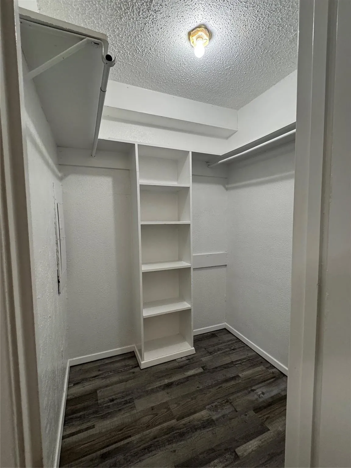 Built-in shelving, hanging rods, wood-finish flooring, and overhead lighting